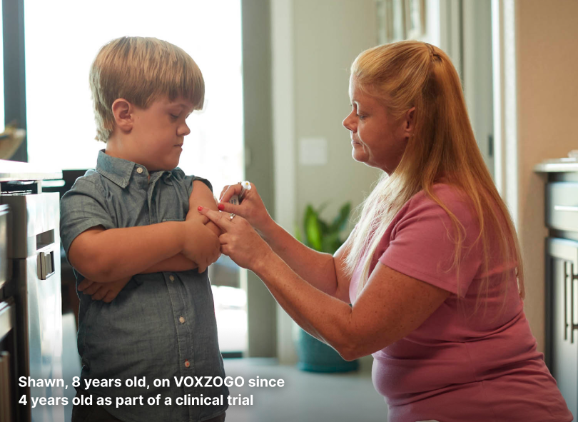 Caregiver preparing to administer a VOXZOGO subcutaneous injection to a young child with achondroplasia