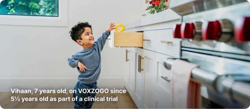 Young child with achondroplasia who is on VOXZOGO treatment, reaching into a kitchen drawer
